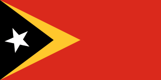 The flag of Timor-Leste has a red field with two isosceles triangles which share a common base on the hoist end. The smaller black triangle, which bears a five-pointed white star at its center and spans one-third the width of the field, is superimposed on the larger yellow triangle that extends to the center of the field.